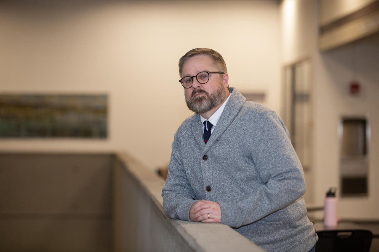 UC Professor Jeffrey Blevins leans on a balustrade for a photo.